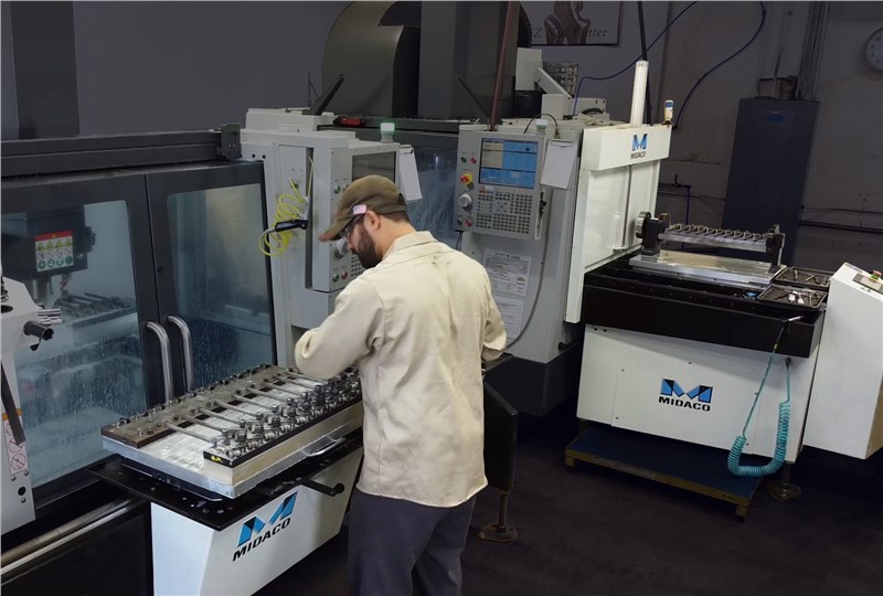 Machinist Loading Parts onto Midaco Manual Pallet Changer with Automatic Pallet Changer in Background