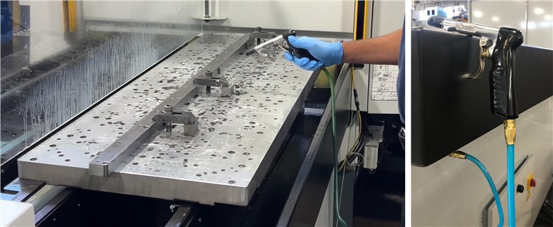 Close up of Midaco pallet on the shuttle and chip shield with machinist using air nozzle to blow coolant off machined parts