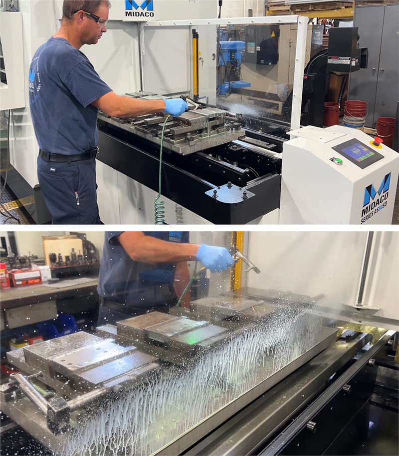 Midaco Automatic Pallet Changer in machine shop with a machinist using an air nozzle to clean off metal chips an coolant against the CNC Chip Shield