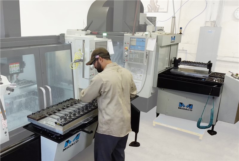 Machinist Loading Parts onto Midaco Manual Pallet Changer with Automatic Pallet Changer in Background