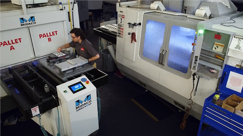 Machinist loading part on Midaco Automatic Pallet Changer in factory with second machine in background