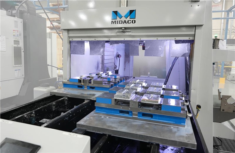 Midaco Automatic Pallet Changer showing pallet swap inside VMC with fixtures and parts on aluminum pallets