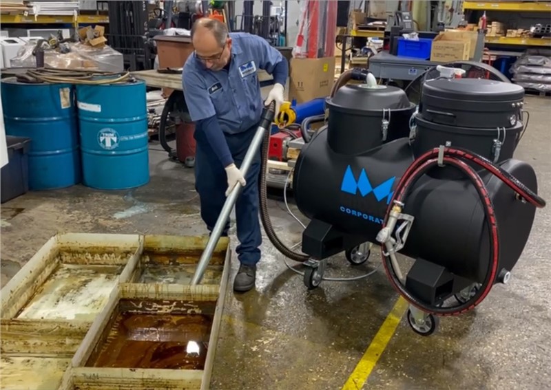 Machinist cleaning VMC tray with Midaco Industrial Vacuum for CNC Chips and Fluids