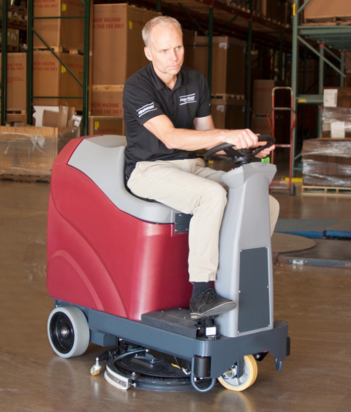 Man Operating a Midaco Ride On Floor Scrubber in a warehouse