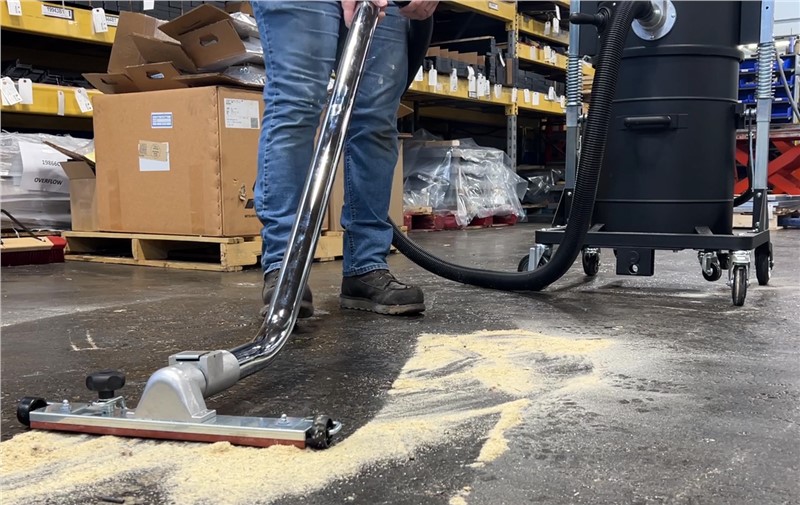 Operator cleaning sawsut from shop floor with Midaco Industrial Dry Vacuum